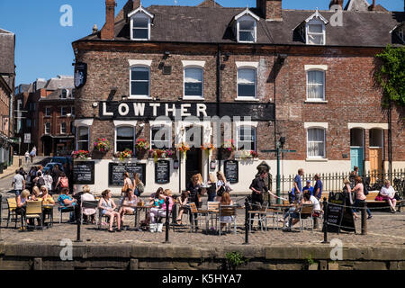 People sat outdoors at the bars and cafes along the banks of the River Ouse in York on a summers day, Yorkshire, England, UK Stock Photo