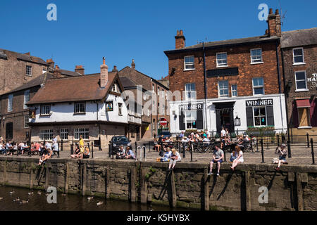 People sat outdoors at the bars and cafes along the banks of the River Ouse in York on a summers day, Yorkshire, England, UK Stock Photo