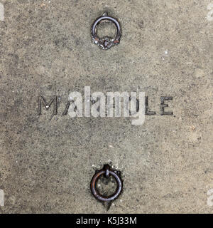 Concrete manhole cover with iron ring handles. Stock Photo