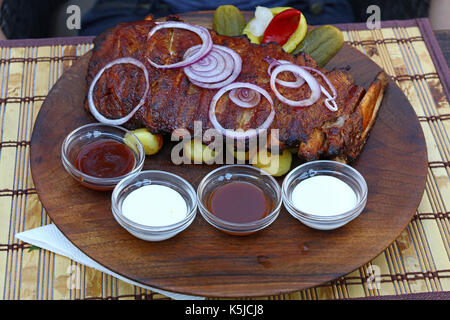 Rack of grill roasted pork spare ribs with onion rings, pepper and sauces, close up, high angle view, personal, perspective Stock Photo