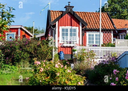 Karlskrona, Sweden - August 28, 2017: Travel documentary of city surroundings. Red and white allotment cabin and garden with flowers. Blue milk barrel Stock Photo