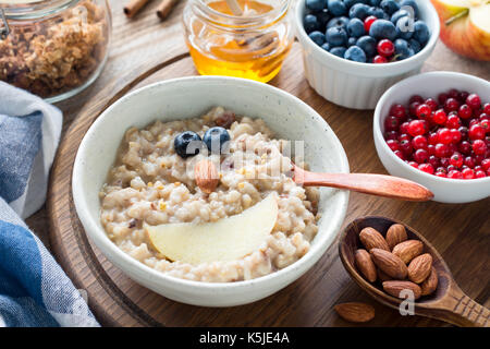 Meal for kids - oatmeal porridge bowl with cute funny face made with fruits. Cozy breakfast food Stock Photo