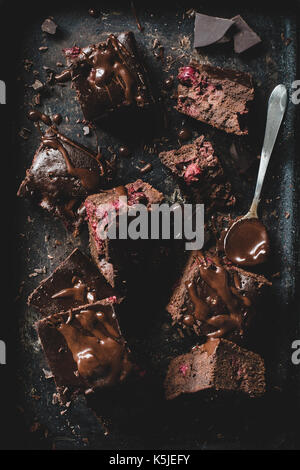 Chocolate cherry brownies decorated with melted chocolate on dark background. Table top view Stock Photo