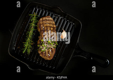 Grilled beef steak in a pan on the black background Stock Photo