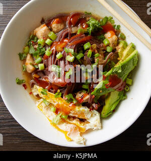 White bowl of chicken and veggie Pho with egg, avocado and sriracha Stock Photo