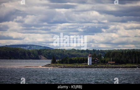 A lighthouse sits on the north western shoreline of Nova Scotia, Canada as seen from a passenger ferry crossing the Northumberland Straight. Stock Photo