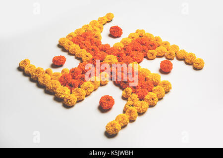 stock photo of hindu auspicious symbol called Swastika made using marigold flower or zendu or genda phool, Flower rangoli in the shape of Swastika for Stock Photo