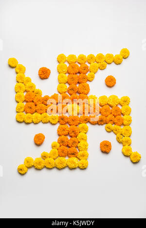 stock photo of hindu auspicious symbol called Swastika made using marigold flower or zendu or genda phool, Flower rangoli in the shape of Swastika for Stock Photo