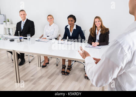Businessperson Having Discussion With Colleague In Office Stock Photo