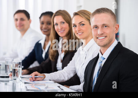Happy Multiethnic Businesspeople Sitting In Row In Office Stock Photo