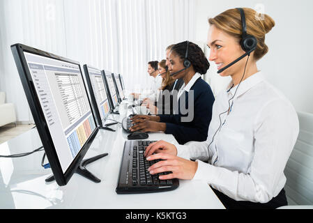 Call Center Operators In A Row Working On Computers In Office Stock Photo