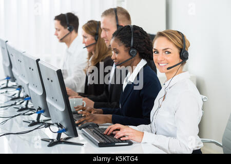 Call Center Operators In A Row Working On Computers In Office Stock Photo