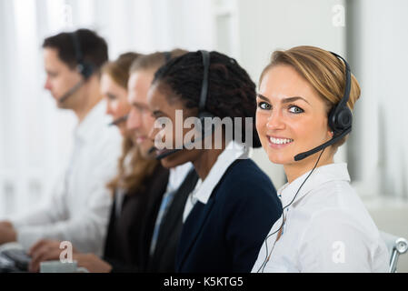 Call Center Operators In A Row Working On Computers In Office Stock Photo