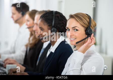 Call Center Operators In A Row Working On Computers In Office Stock Photo