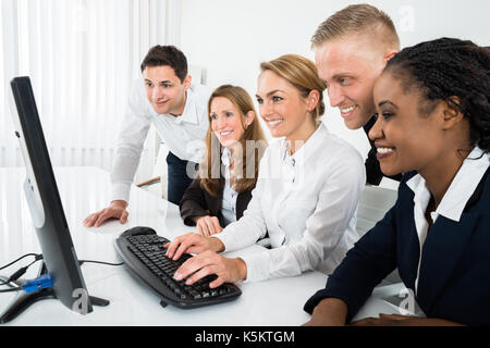 Team Of Businesspeople Looking At Computer In Office Stock Photo