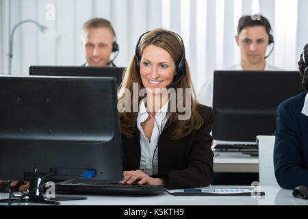 Happy Businesswoman Wearing Headset Working With Colleagues In Office Stock Photo