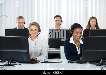Team Of Call Center Operators Working On Computers At Workplace Stock Photo