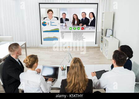 Group Of Businesspeople Discussing Graphs Through Videochat In Office Stock Photo