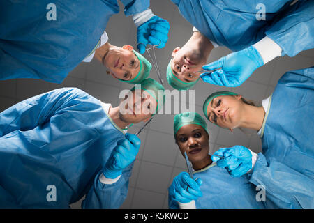 Team Of Surgeons With Medical Instruments Looking At Camera In Operating Room Stock Photo
