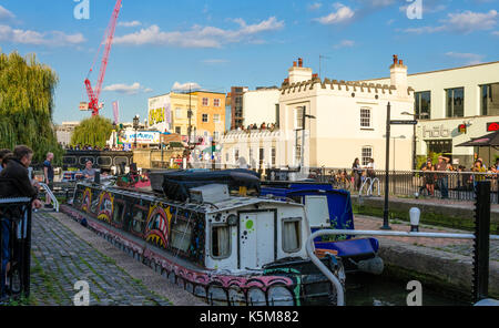 Spectators watch a couple of narrow boas pass through Hampstead Road Lock on The Regent's Canal in Camden Town, London. Stock Photo