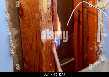 plumber repairs the pipe in the wall Damaged wall plumbing in a house closeup Stock Photo
