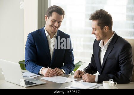 Handsome businessman signing contract with partner Stock Photo