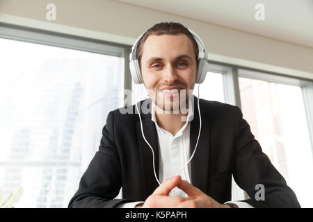 Smiling young businessman in headphones looking in camera. Stock Photo