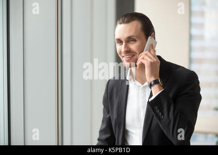 Smiling handsome businessman in suit talking on cellphone. Stock Photo