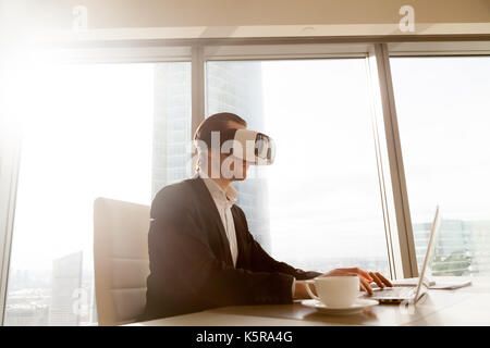 Businessman in VR headset performing application test on compute Stock Photo