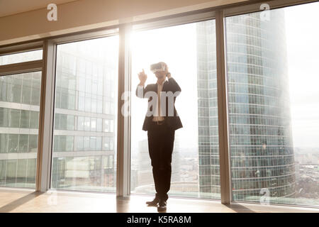 Businessman wears vr headset, pointing finger in the air. Stock Photo