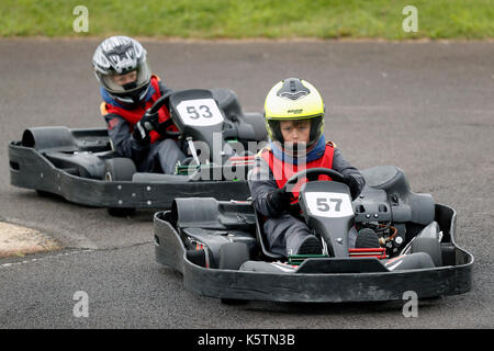 Young boys learn to drive karts on a track during a Junior Karting course at Thruxton racing circuit in Thruxton Hampshire, England Stock Photo