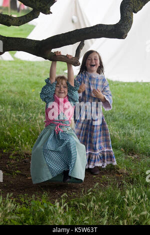 girls swinging on a branch in costume at a reenactment Stock Photo