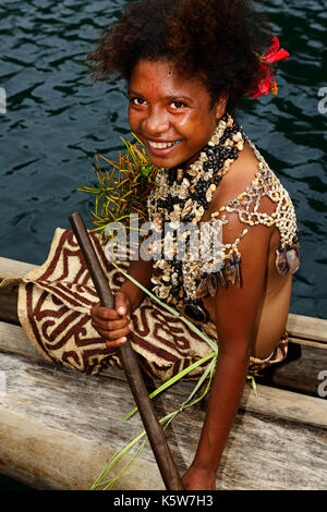 Korafe tribe, girl rowing in dugout boat, traditional tapa clothing from bark, Tufi, Papua New Guinea Stock Photo