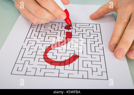 Person Hand With Question Mark On Maze Over Paper Stock Photo