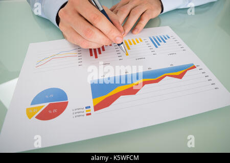 Close-up Of Businessman Analyzing Graphs On Paper Stock Photo
