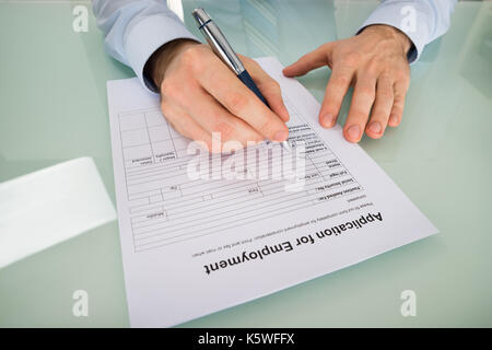 Close-up Of Person Hand Filling Application For Employment Form Stock Photo