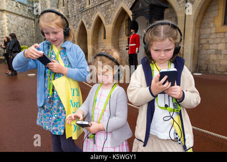 Three sisters /children /kid /kids on holiday listen to an audio guide information while on a tour. Windsor. Berkshire UK.