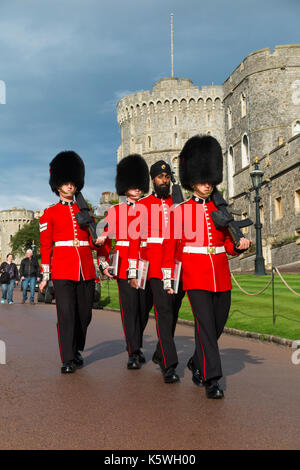 British Army soldiers / Windsor Castle Guard ( 7 Company Coldstream Guards ) wearing traditional red uniform & Bearskin hat / Bearskins & Sikh turban. Stock Photo