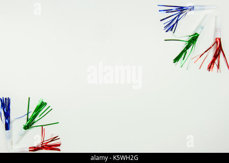 Red, green and blue party noise makers with streamers on white with copy space. Stock Photo