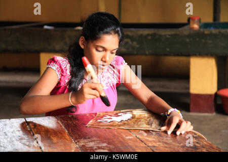 Sri Lanka - January 3, 2017: Young girl hand painting fabric in a local Batik factory - store. Stock Photo
