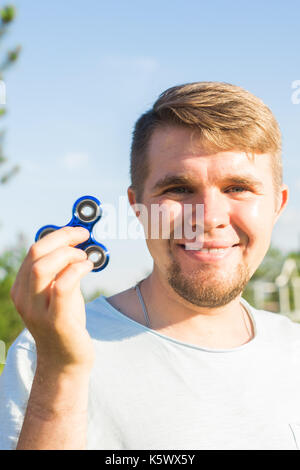 Young man holding and playing with fidget spinner. looking at camera. Stock Photo