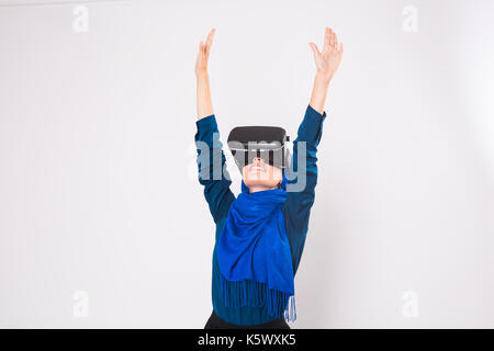 Asian muslim woman wearing hijab using VR headset glasses of virtual reality on white background. Stock Photo