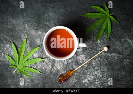 Marijuana tea and leafs on a dark textured background Stock Photo