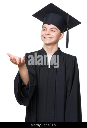 Portrait of graduate teen boy student in black graduation gown with hat - isolated on white background. Child back to school and educational concept. Stock Photo