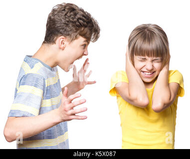 Emotional portrait of brother and sister, quarreling children - teen boy shouting at little girl. Negative human face expression. Conflict concept. Stock Photo