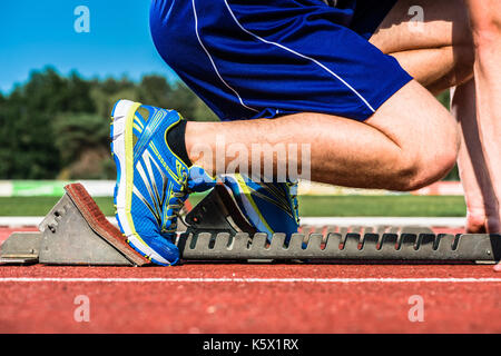 Runner before start signal on starting block of sprint track in sport stadium Stock Photo