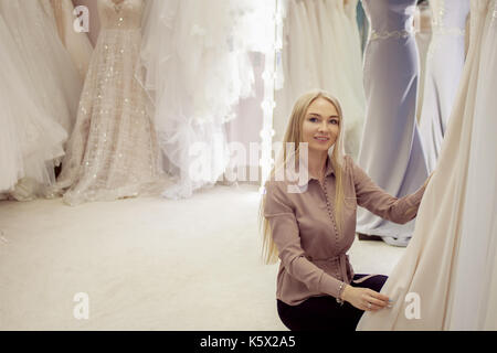Beautiful girl chooses her wedding dress. Young woman entrepreneur. Portrait in Bridal salon Stock Photo