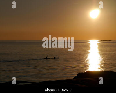 Two people paddling kayak into the sun set. Ouyside of Hönö, Klåva, Gothenburg, on the west coast of Sweden. Stock Photo