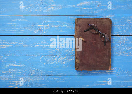 Glasses on the closed Bible on a blue wooden background. Stock Photo