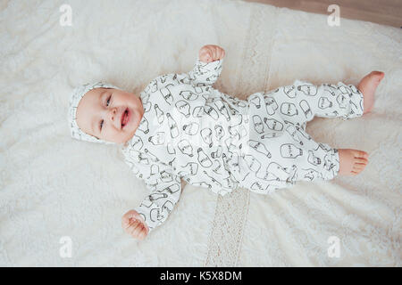 Newborn baby dressed in a suit on a soft bed in the studio. Stock Photo